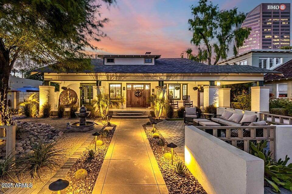 Historic Phoenix home at dusk with palm trees and the downtown skyline behind
